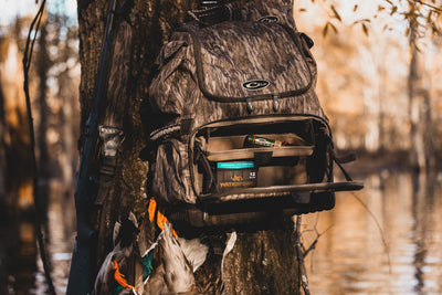 Tree Hugger Timber Pack with camo pattern, open to show Waterfowl shotgun shells, shotgun, and harvested ducks, demonstrating its rugged design and ample hunter storage features.