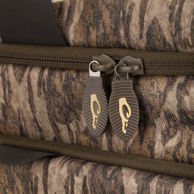 Close-up of Tree Hugger Timber Pack, highlighting a camo fabric with olive zipper and brown pulls, designed for durable hunting gear storage and organization.