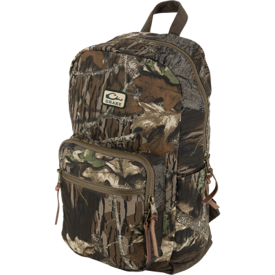 Waterfowl Throwback 80 Backpack in Mossy Oak Original Break Up features cotton canvas, two zippered compartments, brown straps, and a small DRAKE logo patch on the upper front pocket.