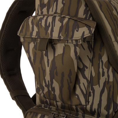 Tree Hugger Timber Day Pack close-up, showing camouflage pattern, front pocket with flap, padded shoulder strap, and zipper pull from lower compartment for outdoor gear access.