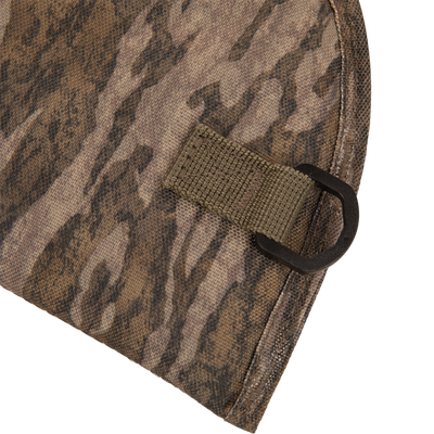 Close-up of The Migrator Gun Case's camouflage fabric with an olive-drab loop and D-ring, highlighting its durable, waterproof design for professional field use.