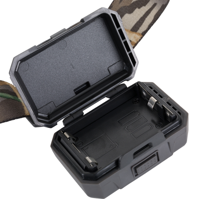 A close-up of an open black plastic battery compartment with visible metal contacts and a camouflage strap attached—ideal for the Waterfowl 3 Headlamp Lighting Pack 250LM.