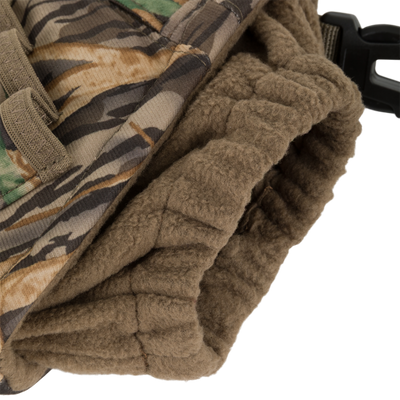 Close-up of a camouflage fabric with a brown fleece-lined cuff and black plastic buckle, highlighting the windproof handwarmer design of the Waterfowl LST Handwarmer Muff.