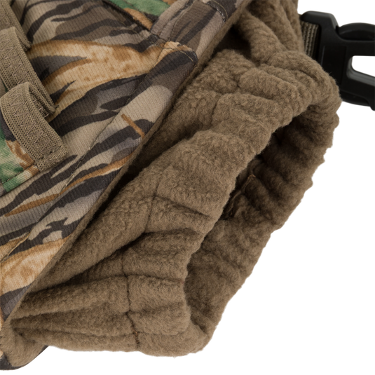 Close-up of a camouflage fabric with a brown fleece-lined cuff and black plastic buckle, highlighting the windproof handwarmer design of the Waterfowl LST Handwarmer Muff.