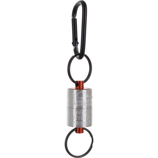 A metallic cylindrical Drake Finisher Magnetic Retractor for waterfowl hunting, featuring orange accents and split rings attached to a black carabiner.