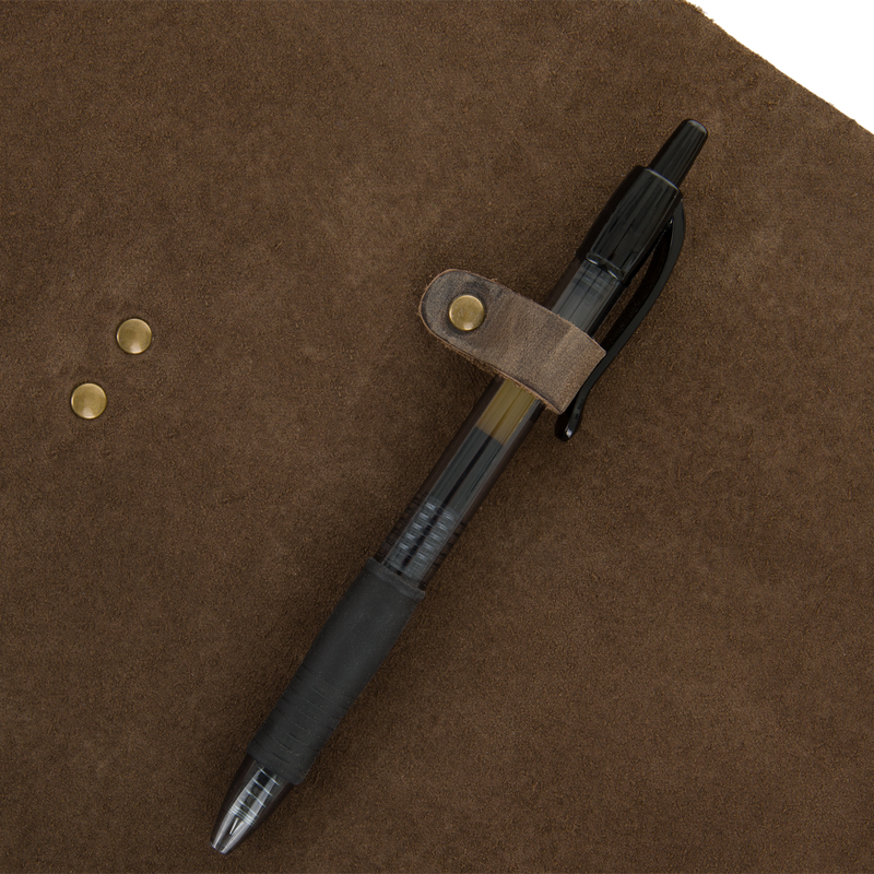 Drake Leather Wingshooters Hunting Log features a brown suede cover with brass rivets, a leather strap, and a pen-holder loop securing a black ballpoint pen.