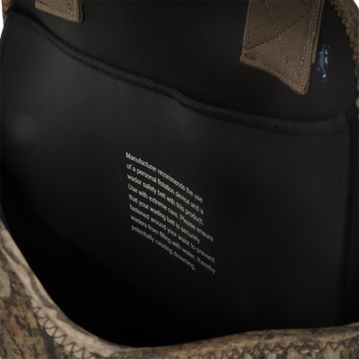 Close-up of the inside pocket of the Waterfowl Youth Neoprene Wader, featuring a white printed safety warning, brown stitching, and space for an adjustable belt or Thinsulate Buckshot Mud Boot.