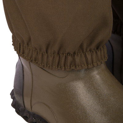 Close-up of the Hardline Uninsulated Breathable Wader's elasticized hem snugly wrapped around a rubber boot, showcasing durable waterproof construction for outdoor adventures.