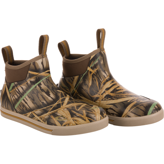 The Waterfowl Camp Deck Boot features ankle-high neoprene, Mossy Oak Original Shadow Grass camo, beige soles, and front/back pull tabs.