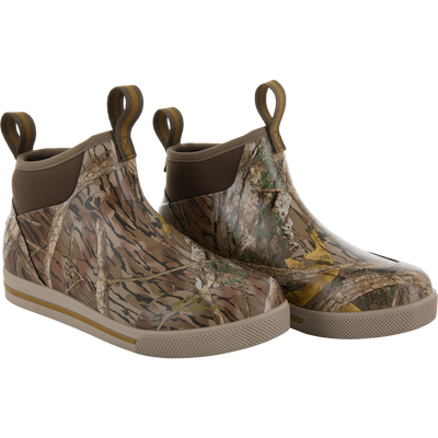 The Camp Deck Boot by Waterfowl features a Mossy Oak Shadow Branch camo pattern, waterproof neoprene construction, ankle-high design, and looped pull tabs at the back.