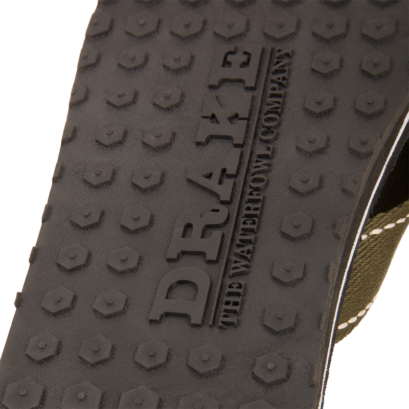 Close-up of Lake Shore Flip Flops' rubber tread with hexagonal pattern and embossed DRAKE, featuring olive-green strap edge, ideal for water adventures.