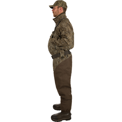 Uninsulated Guardian Elite HND Front Zip Waders: A man turned to the side wearing waders with Internal handwarmer pockets to keep your hands warm and protected on even the coldest days .