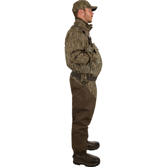Uninsulated Guardian Elite HND Front Zip Waders: A man turned to the side wearing waders with Internal handwarmer pockets to keep your hands warm and protected on even the coldest days .
