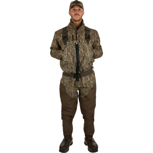 Uninsulated Guardian Elite HND Front Zip Waders: A man wearing waders with Internal handwarmer pockets to keep your hands warm and protected on even the coldest days .