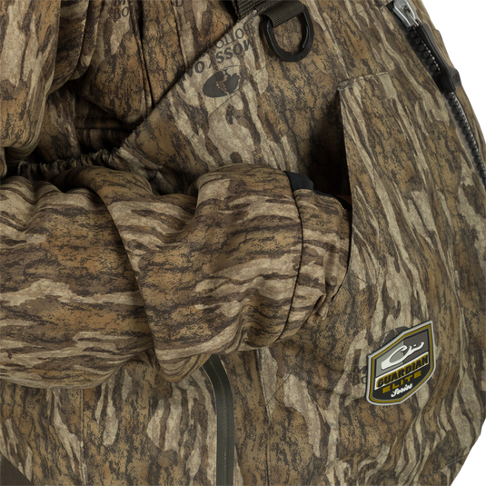 Person wearing the Insulated Guardian Elite HND Front Zip Wader with visible camouflage pattern and logo, highlighting durable construction and reinforced taped seams for hunting.