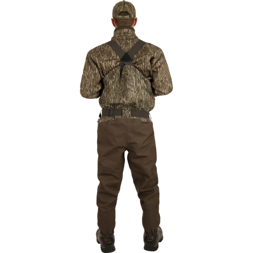 A man wearing the Insulated Guardian Elite HND Front Zip Wader with camouflage jacket and hat, showcasing durable, waterproof hunting gear with Thinsulate® boot lining.