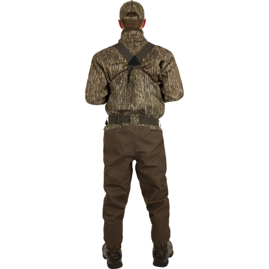 A man wearing the Insulated Guardian Elite HND Front Zip Wader with camouflage jacket and hat, showcasing durable, waterproof hunting gear with Thinsulate® boot lining.