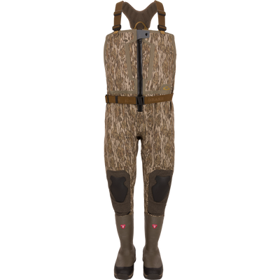 The Waterfowl BMF1600 Kevlar Wader in Mossy Oak Bottomland features brown suspenders, knee pads, and attached rubber boots—ideal for fishing or hunting. Displayed on a plain white background.