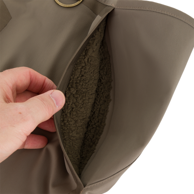 A hand opens a fleece-lined chest pocket on these brown Drake X Ducks Unlimited BMF1600 Kevlar Wader waterproof hunting waders.