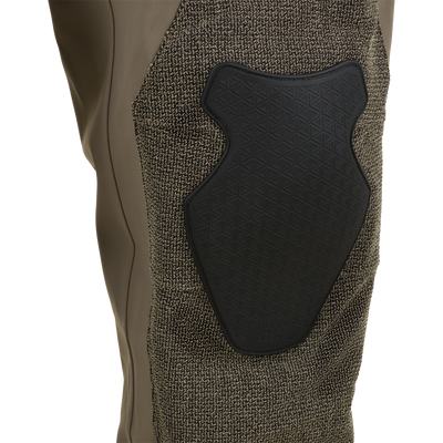 Drake X Ducks Unlimited BMF1600 Kevlar Wader in olive-drab, featuring a textured brown fabric overlay on the knee and a black, shield-shaped protective pad embossed with a geometric pattern.