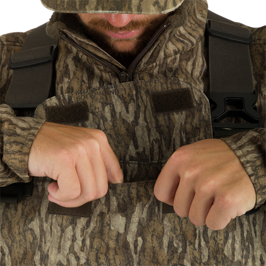 A man wearing the Insulated Guardian Elite Vanguard Breathable Waders featuring front cargo pouch.