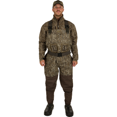 A man in camouflage uniform wearing Insulated Guardian Elite Vanguard Breathable Waders, standing confidently.