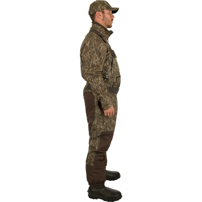 A man wearing the Insulated Guardian Elite Vanguard Breathable Waders, designed for cold conditions. Waterproof, windproof, and breathable with reinforced seams and high-wear HD2 material. Stay warm with LokDown insulation and Thinsulate Buckshot Mudder boots. Features include handwarmer pockets, cargo pouch, and zippered pocket. Perfect for hunting.