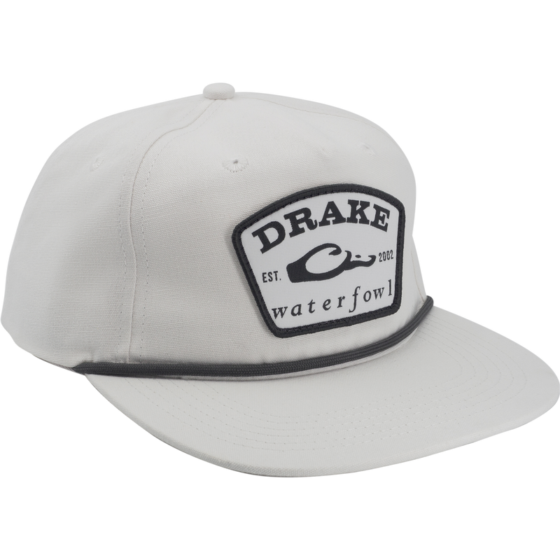 Drake X Lost Hat Drake Patch Goat Rope Cap with a stitched shield patch, flat brim, adjustable snap-back, and paracord detail, blending comfort and support.