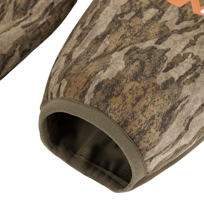 A close-up of a sleeve with a forest camouflage pattern and olive green elastic cuff from the Non-Typical Midweight Nova Silencer Jacket with Scent Control by Nontypical.