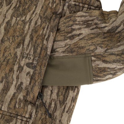 A close-up of a Non-Typical Midweight Nova Silencer Jacket with Scent Control sleeve featuring a green inner cuff, zippered pocket, detailed camo pattern, textured fabric, and advanced scent control by Nontypical.