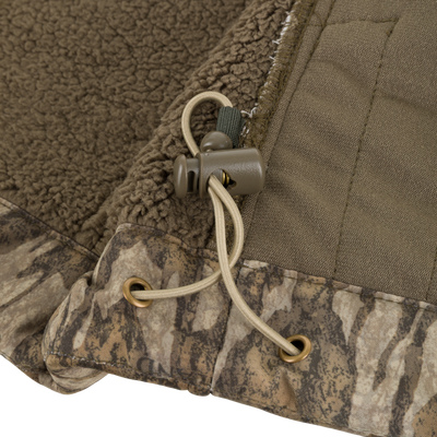 Close-up of the Non-Typical Midweight Nova Silencer Jacket with Scent Control by Nontypical, featuring brown and camo fabric, beige drawstring with cord lock, metal grommets, and soft sherpa fleece lining.