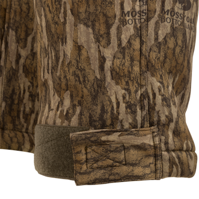 Close-up of the Midweight Nova Silencer Pant's hem, featuring Mossy Oak camo print and adjustable Velcro tab for a snug fit.