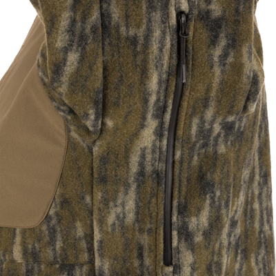 Close-up of the green and brown camouflage-patterned Non-Typical Midweight Hydrowool Softshell Jacket with Scent Control by Nontypical, showing a black zipper, tan patch, and its water-resistant, fleece-like texture.