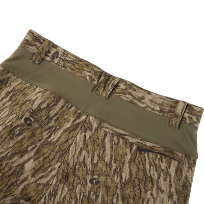 Close-up of forest camo Non-Typical SWT Pant with Scent Control by Sale, featuring an olive waistband, belt loops, flexible SWT stretch fabric, and a subtle logo on the rear pocket for comfort and style.