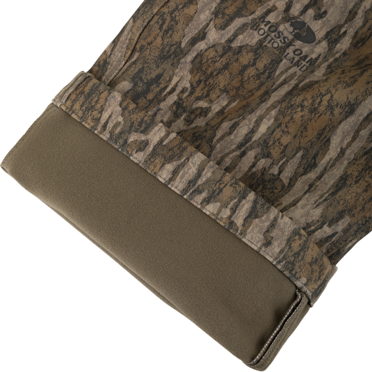 Close-up of a Non-Typical Pursuit Softshell Pant with Agion Active X2 cuff, featuring a woodland camouflage pattern with a solid olive-green interior lining.