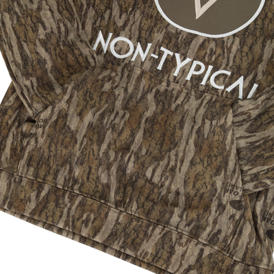 Close-up of the Non-Typical Youth Performance Hoodie with Agion Active X2 by Nontypical, featuring a brown and green camouflage tree bark pattern, NON-TYPICAL circular logo, large front pocket, and anti-odor technology.