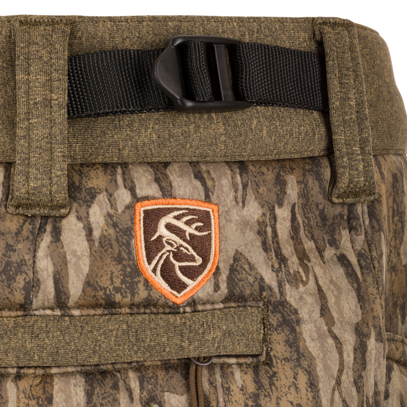 Close-up of Silencer Soft Shell Pant with Agion Active XL, featuring camouflage pattern, adjustable waist, and pockets. Ideal for quiet, comfortable hunting.