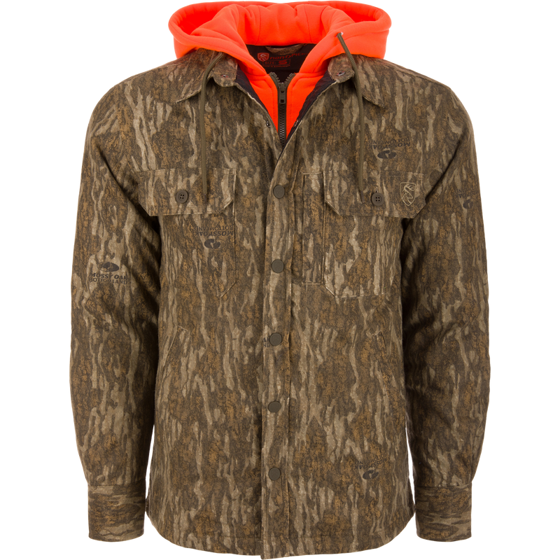 Men’s hunting-style jacket with Mossy Oak Bottomland camo, featuring blaze-orange hood, snap closure, and chest pockets, showcasing Drake Waterfowl's durable, functional hunting apparel.