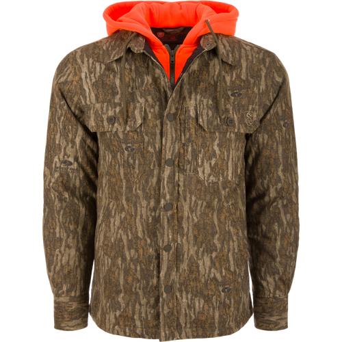 Men’s hunting-style jacket with Mossy Oak Bottomland camo, featuring blaze-orange hood, snap closure, and chest pockets, showcasing Drake Waterfowl's durable, functional hunting apparel.