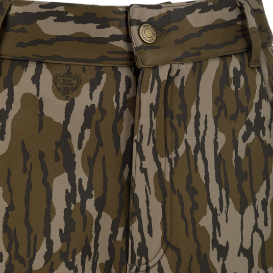 Close-up of Nontypical Youth Endurance Pant with brown, green, and black camo, scent control, waistband with belt loop and button closure, plus a subtle left-side logo.
