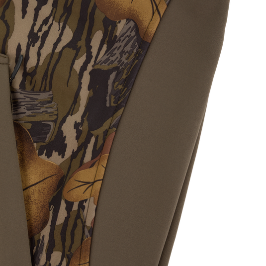 Close-up of a Non-Typical Endurance Hooded Full Zip Jacket with Scent Control, featuring solid olive green panels and panels with a brown and green camouflage pattern of tree bark and leaves.