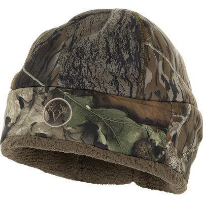 The Non-Typical Silencer Sherpa Fleece Beanie by Nontypical features a camouflage pattern, soft brown lining, and an embroidered antlers logo—offering warmth and comfort.