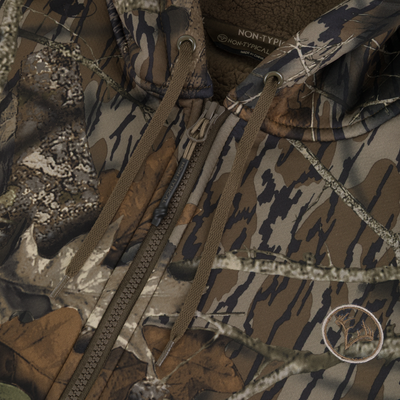 Close-up of the Non-Typical Slacker Quarter Zip Hoodie by Nontypical, featuring a camo pattern, brown drawstrings, deer antler patch, and thick fleece lining—perfect for hunting or outdoor use.