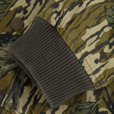 Close-up of the Campfire Canvas Bomber Jacket sleeve shows a camouflage pattern with a ribbed, dark olive green cuff and a partially visible brown button near the seam. Brand: Lifestyle.