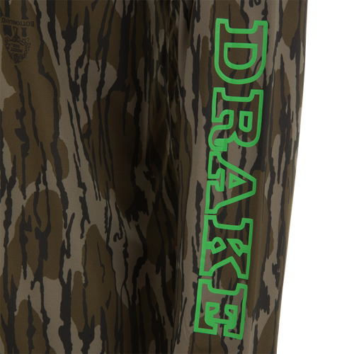 Lake Shore Performance Long Sleeve Hoodie featuring a brown/olive tiger-stripe camo pattern with a Mossy Oak logo, ideal for cooling and sun protection during outdoor activities.