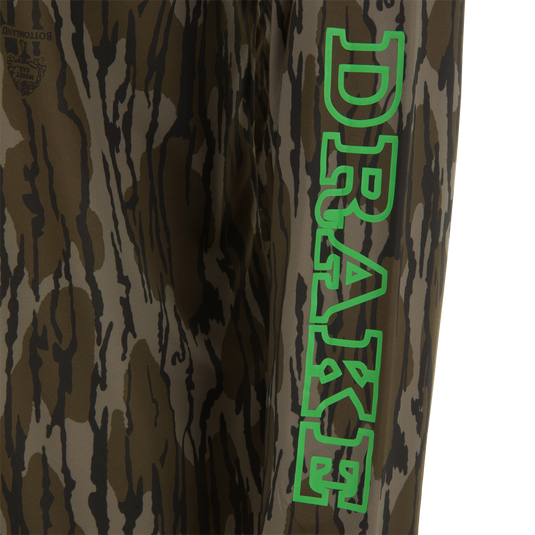 Lake Shore Performance Long Sleeve Hoodie featuring a brown/olive tiger-stripe camo pattern with a Mossy Oak logo, ideal for cooling and sun protection during outdoor activities.