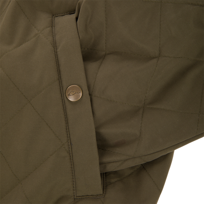 Close-up of the Delta Quilted Jacket by Lifestyle in olive green, showcasing a pocket with a metal logo button and diamond quilting—blending stylish design with outdoor performance durability.
