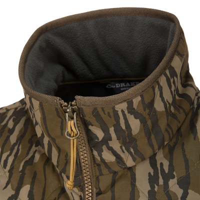 Close-up of a Lifestyle Delta Quilted Vest in brown and green camouflage, featuring a gray fleece-lined collar and a zippered front.