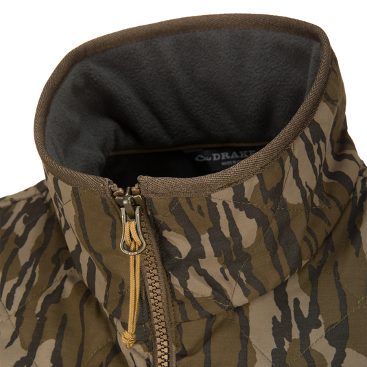 Close-up of a Lifestyle Delta Quilted Vest in brown and green camouflage, featuring a gray fleece-lined collar and a zippered front.