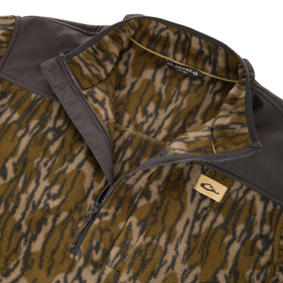 Camp Fleece Over Under Quarter Zip in a brown and green camouflage pattern with solid brown shoulder panels and a logo patch on the chest.